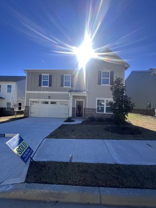 Street view A charming two-story home with a bright facade in Ashford Park by Starlight Homes (Covington, GA).