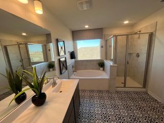 Model Home A bright master bathroom in a Medina Crossing home, featuring a soaking tub, a glass-enclosed shower, dual sinks, and unique patterned tile flooring (Von Ormy, TX).