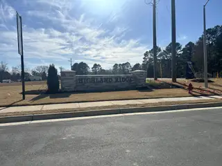 A welcoming stone entrance with clear signage for Highland Ridge by Ryan Homes in Willow Spring, NC.