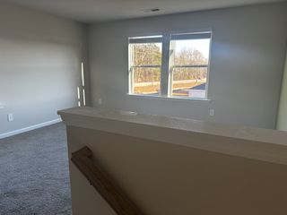 A bright room with neutral walls, carpeted flooring, and large windows offering natural light and scenic views.