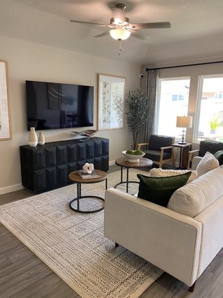 Model Home A modern living room with a plush sofa, smart TV, and elegant decor featuring green accents and natural light.