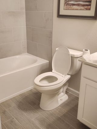 A modern bathroom with neutral-toned tile, a sleek white vanity, and a built-in bathtub for a functional and elegant design.