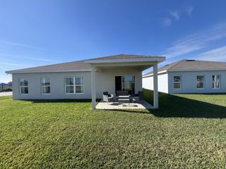 A modern single-story home with a covered patio and lush lawn in Laurel Glen by Ryan Homes (Haines City, FL).