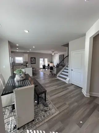 An open-concept living area with wooden flooring, modern dining setup, and a cozy living room. Bright and inviting space.