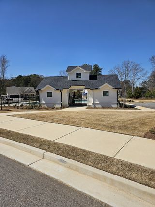 A charming white cottage with a sleek black roof at Hellen Valley by McKinley Homes in Braselton, GA.