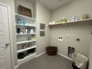 Model Home A functional laundry room with beige walls, built-in white shelving, and ample storage solutions.