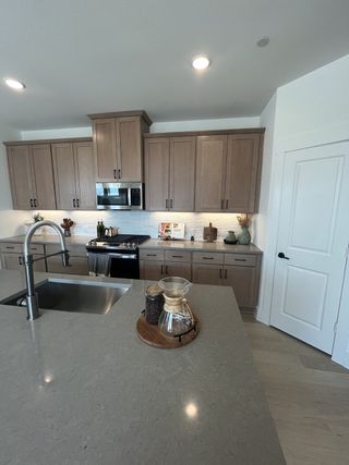 A contemporary kitchen with warm wood cabinetry, sleek countertops, and a large island in Solterra Texas by Cadence Homes (Mesquite, TX).
