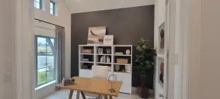 A stylish home office with high ceilings, built-in shelving, and a dramatic dark accent wall for a bold and modern feel.