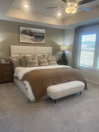 Cozy bedroom with a plush bed, neutral tones, elegant lighting, and a serene painting, creating a tranquil retreat.