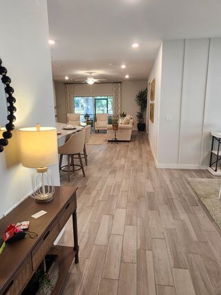 A spacious living area with wood-style flooring, comfy seating, and abundant natural light.