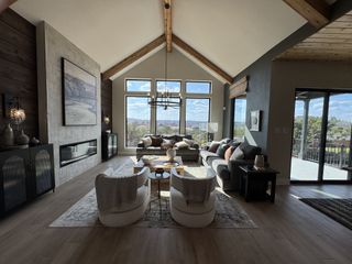 A spacious living room with vaulted ceilings, a modern fireplace, and large windows showcasing panoramic views.