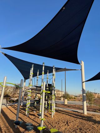 Community Amenities A modern playground with shade sails and climbing structures in Copper Falls by D.R. Horton (Buckeye, AZ).
