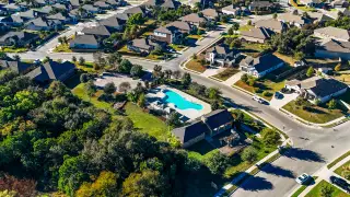 Aerial view of Cypress Forest by Scott Felder Homes in Kyle, TX, featuring a community pool and lush green landscape.