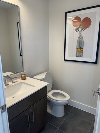 A modern bathroom featuring a sleek vanity, elegant artwork, and dark floor tiles for a stylish touch.