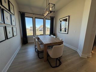 Model Home A stylish dining area with a rustic wood table, elegant lighting, and large windows offering scenic views.