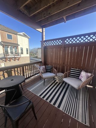 A cozy outdoor patio with stylish seating, a striped rug, and privacy fencing for relaxation.