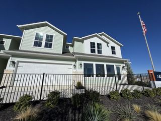 A modern green home with large windows and a manicured yard in Avery Centre by Pacesetter Homes (Round Rock, TX).