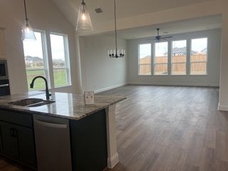 Model Home Open-concept kitchen and living area with large windows, wood flooring, and a sleek island countertop.