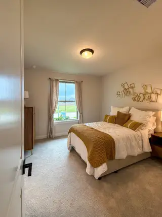 A cozy bedroom featuring warm lighting, plush bedding, and contemporary decor with a scenic window view.