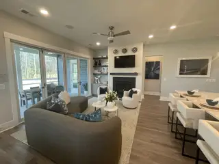 Model Home A cozy living space with a modern fireplace, plush seating, and large sliding glass doors leading to a patio.