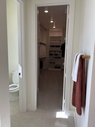 Model Home A spacious walk-in closet with organized shelves, adjacent to a bathroom with modern fixtures and soft lighting.