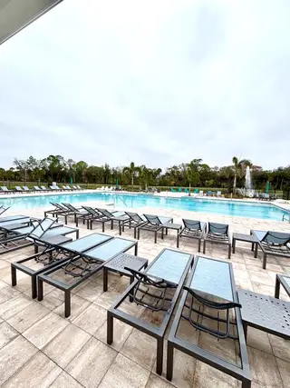 A luxurious pool area with sleek lounge chairs and serene surroundings, perfect for relaxation.