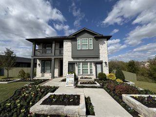 Elegant stone and siding home with lush landscaping in Whisper Valley by Terrata Homes (Manor, TX).