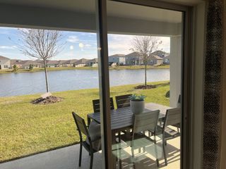 A serene patio view with a dining set overlooking a tranquil pond and landscaped yard, perfect for relaxation.