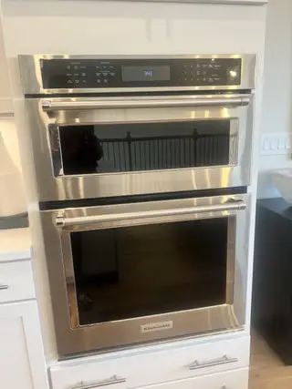 A sleek KitchenAid 27-inch combination wall oven with microwave and convection features a modern stainless steel finish and digital controls.