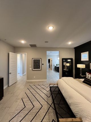 A modern bedroom with sleek lighting, abstract art, and a cozy patterned rug in a stylish neutral palette.