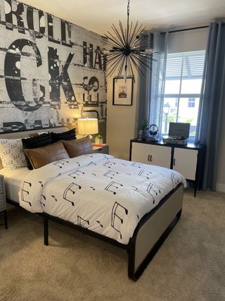 A stylish bedroom with an industrial mural, modern chandelier, and bold decor in Tuscan Springs by Lennar (Pembroke Pines, FL).