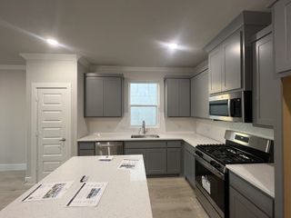 A modern kitchen with sleek gray cabinets, stainless steel appliances, and a spacious quartz island.