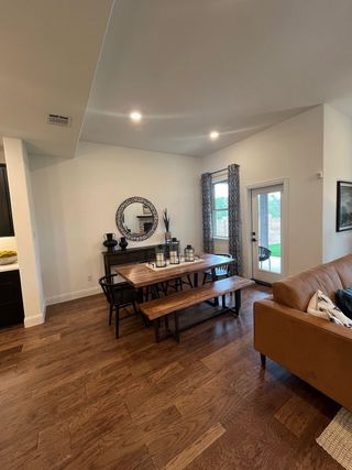 Model Home A cozy dining area with wooden floors, a rustic table, and modern accents, opening to a bright outdoor view.