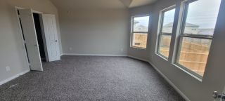 A spacious bedroom with soft carpet, large windows, and an open closet offering ample natural light and cozy comfort.
