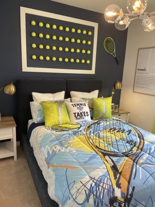 Model Home A playful bedroom with a tennis theme, featuring a colorful bedspread and creative wall art with tennis balls.