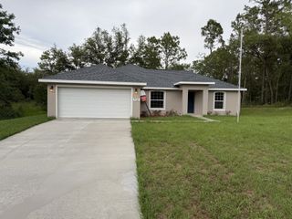 A charming beige home with a spacious driveway in Marion Oaks by Perfect Deed Homes in Ocala, FL.