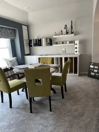 Model Home A cozy design room with lime green chairs, plush carpet, and samples of fixtures and materials on display.