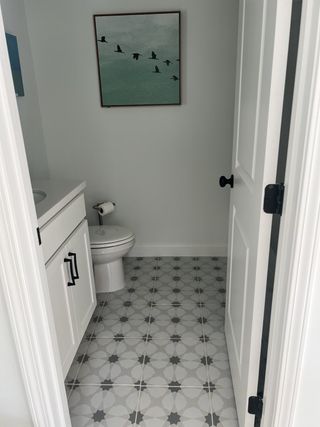 Model Home A chic powder room with patterned tile flooring, white vanity, and modern bird-themed wall art.