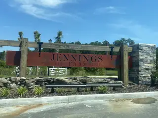 A welcoming entrance to Jennings Farm by Dream Finders Homes in Middleburg, FL, marked by rustic stone and wood accents.