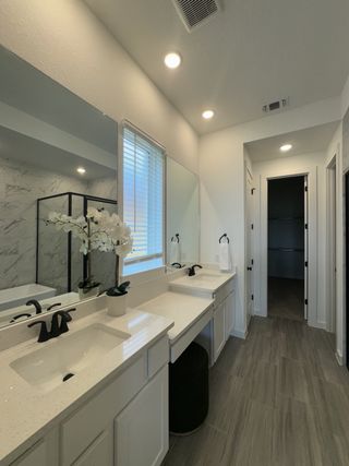 A luxurious bathroom with a dual vanity, elegant white countertops, and a glass-enclosed shower with marble tile accents.