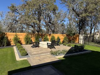 Model Home A cozy backyard retreat in La Cima by Highland Homes (San Marcos, TX), featuring a stone fire pit, lush greenery, and a stylish paved patio.