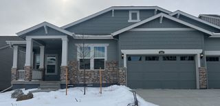 A charming gray home with stone accents and a snow-dusted yard in Macanta: The Grand Collection by Lennar (Castle Rock, CO).