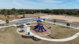Community Amenities A vibrant playground with blue slides and benches in the family-friendly Riverview community by Brightland Homes (Georgetown, TX)