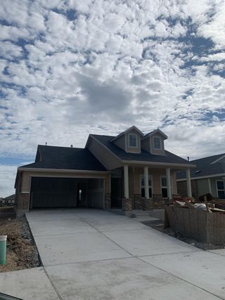 Charming home with a covered porch and spacious driveway in Waterstone: Classic Collection by Lennar (Kyle, TX).