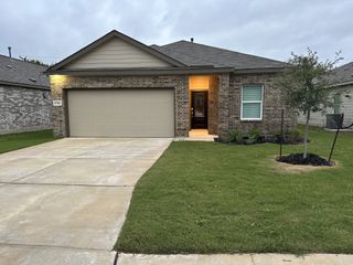 A charming brick home with a two-car garage and lush greenery in Waterwheel by Lennar (San Antonio, TX).