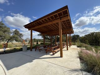 A serene outdoor pavilion with picnic tables in Wolf Ranch by Pulte Homes, Georgetown, TX, surrounded by natural beauty.