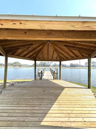 Wooden pavilion leading to a dock over a lake. Peaceful waterside setting with a covered roof providing shade and relaxation.
