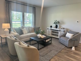 A cozy living room with a plush sofa, accent chairs, stylish decor, and natural light filtering through large windows.