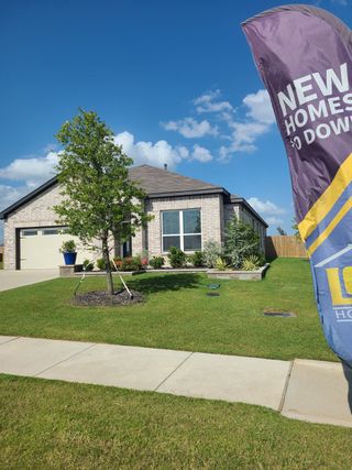 Street view A charming brick home with lush landscaping in Patriot Estates by LGI Homes (Venus, TX).
