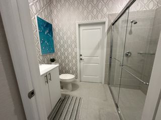 A modern bathroom with geometric wallpaper, a sleek glass shower, and stylish vanity.